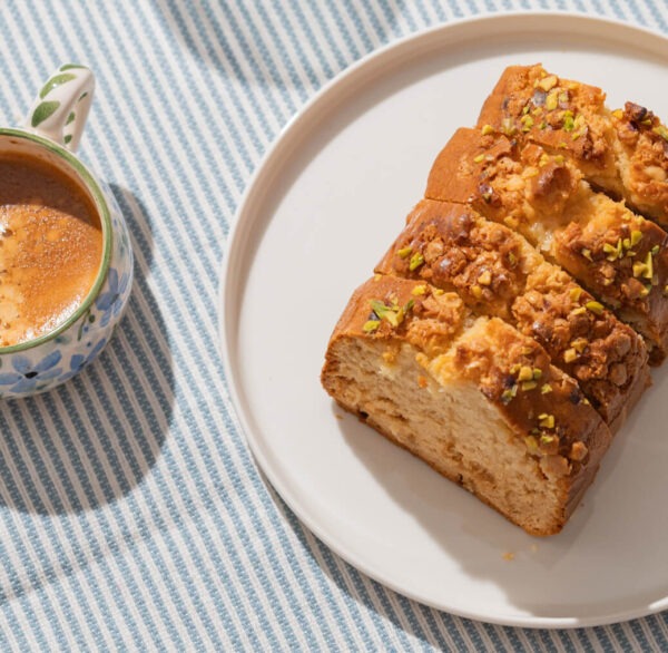 Banana nut flavored coffee brewed in a cup next to a plate of banana bread