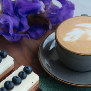 Blueberr Cinnamon Crumble flavored coffee in a cup next to some blueberry desserts