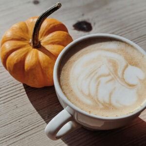 Pumpkin spics flavored coffee in a cup next to a mini pumpkin