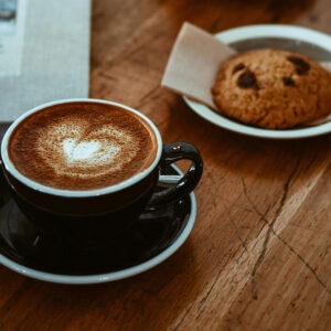 Snickercookie flavored coffee in a coffee cup next to a Snickerdoodle cookie