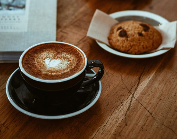 Snickercookie flavored coffee in a coffee cup next to a Snickerdoodle cookie